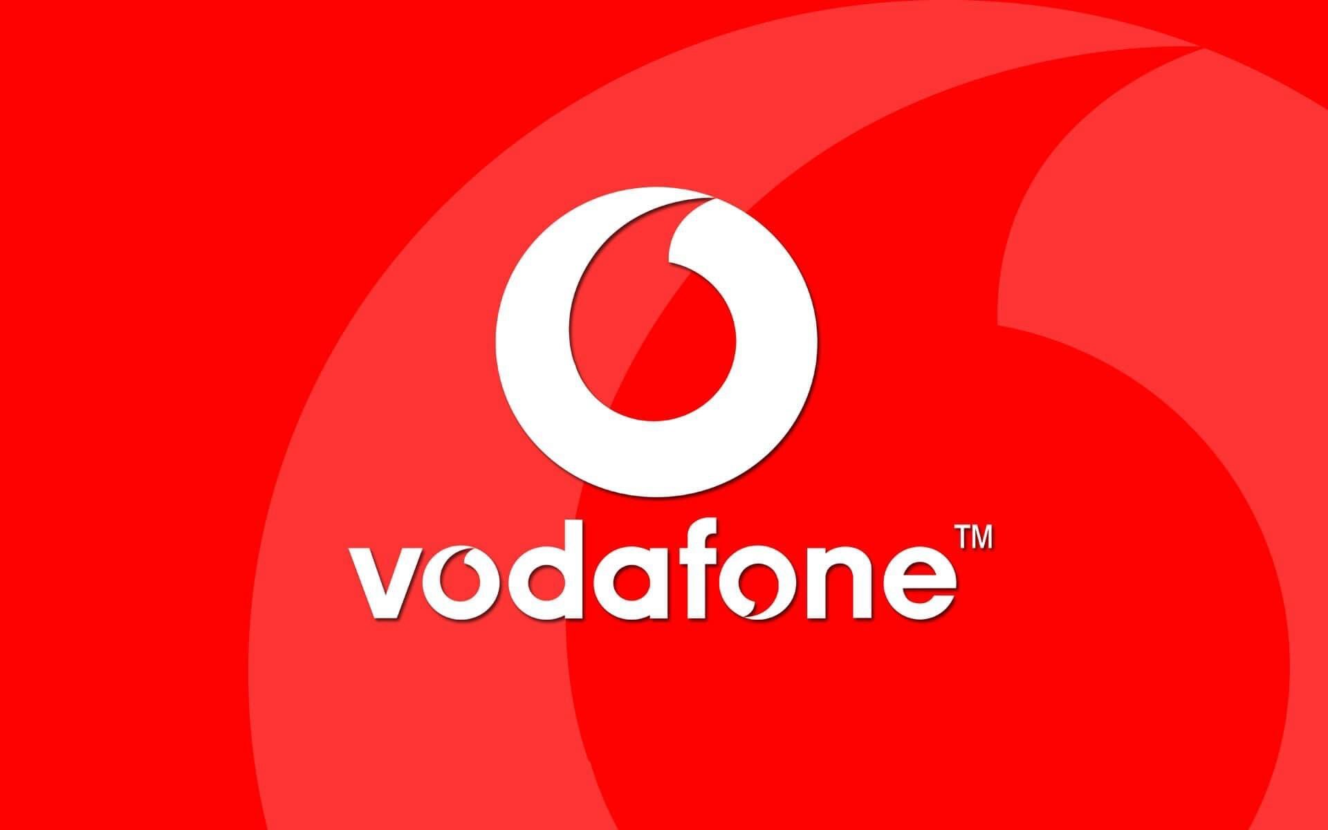 A modern telecommunications tower with a Vodafone logo, set against a backdrop of a bustling U.S. city, symbolizing the company's enterprise network expansion in the USA.