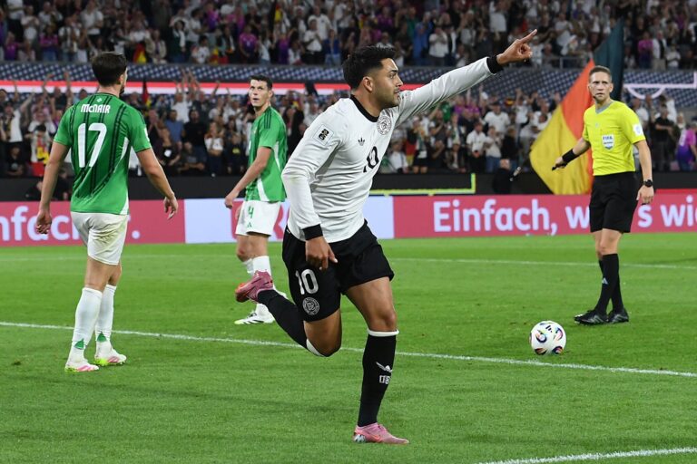 Action-packed moment from the Nordirland vs. Deutschland WM-Qualifikation 2025 match at Windsor Park, Belfast, with players competing for the ball under a vibrant stadium atmosphere.
