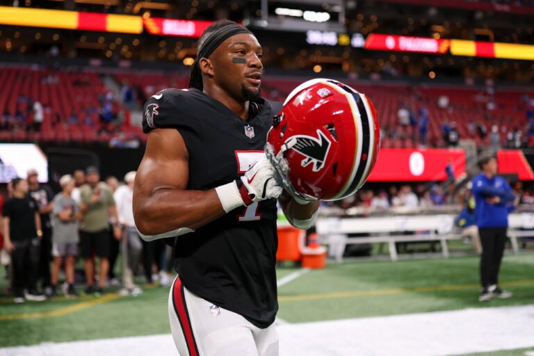 Atlanta Falcons running back Bijan Robinson sprints down the field, evading a defender during an NFL game, showcasing his speed and agility as a rising star.