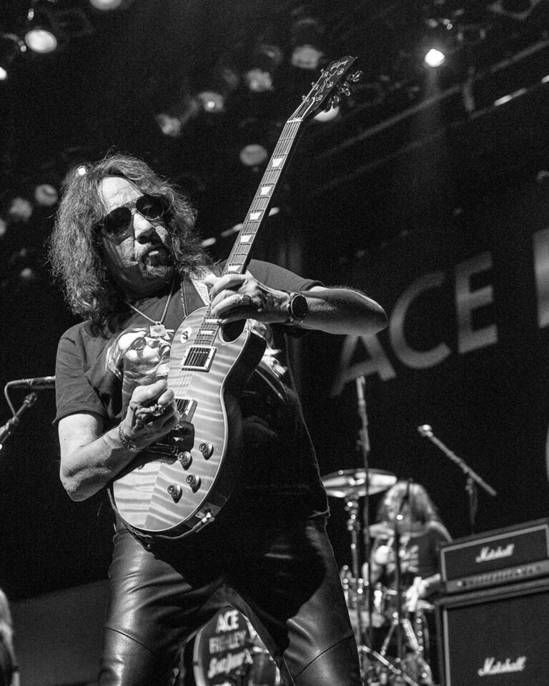 Ace Frehley, renowned lead guitarist of Kiss, poses with his guitar and signature stage outfit, highlighting his influential role in rock music history