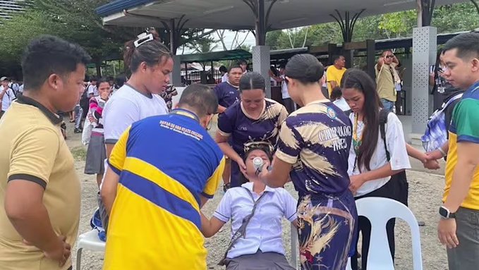 Damaged building in Mindanao after the Philippines earthquake tsunami alert, with debris and evacuees in the foreground.